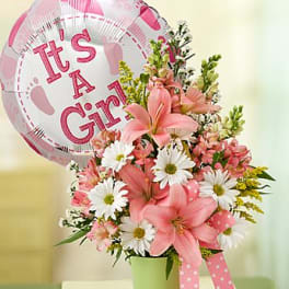 Pink lilies and white daisies in a green pot with a pink 'It's a Girl' balloon and polka dot ribbon