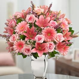 Pink roses, lilies, and gerbera daisies arranged in a clear glass vase