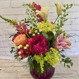 Mixed bouquet in a purple vase with pink, yellow, and white blooms
