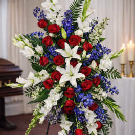 Standing floral spray with red roses, white lilies, and blue flowers