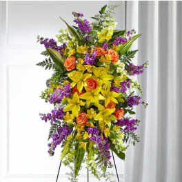 Tall standing floral spray with yellow lilies, orange roses, and purple flowers