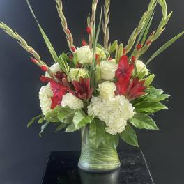 Red and white floral arrangement in a glass vase