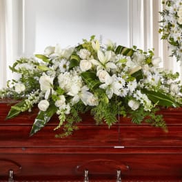 White floral casket spray with lilies, roses, and daisies