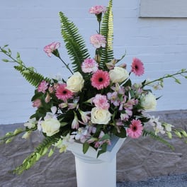 Pink and white floral arrangement in a white pedestal vase