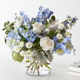 Blue and white flower arrangement in a clear glass vase