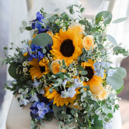 Bouquet of sunflowers, peach roses, and blue flowers on a chair