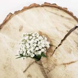 Small white baby's breath bouquet tied with twine on a wood slice