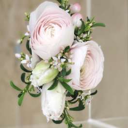 Pink ranunculus boutonniere with white blossoms and greenery