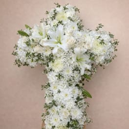 White floral cross arrangement on a wooden easel