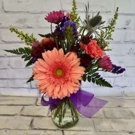 Mixed bouquet with a peach gerbera daisy in a glass vase