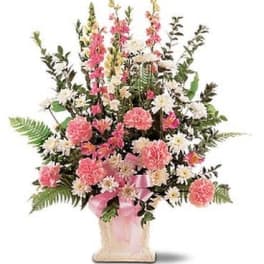 Pink and white floral arrangement in a square vase with a pink ribbon