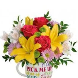Bouquet of red roses and yellow lilies in a printed mug