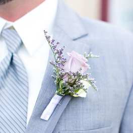 Boutonniere with a pale pink rose on a gray suit lapel