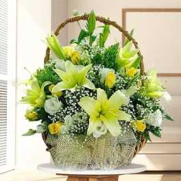 Basket arrangement of yellow lilies and white roses with baby's breath