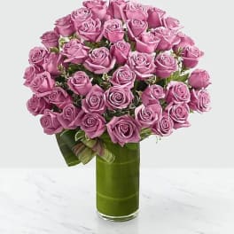 Pink rose bouquet in a tall green glass vase