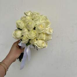 Handheld bouquet of cream white roses tied with a white ribbon