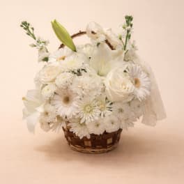 White floral basket arrangement with lilies, roses, and daisies