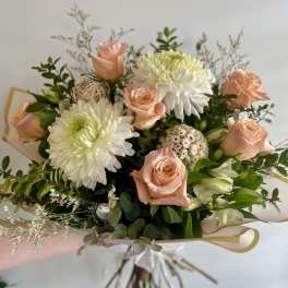 Hand-tied bouquet of peach roses and white mums with dried accents in pale wrapping