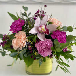 Pink and peach floral arrangement in a square glass vase