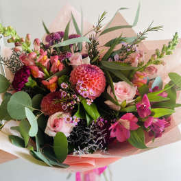 Bouquet of pink roses, dahlias, and snapdragons wrapped in pink paper