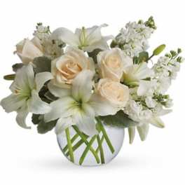 Low arrangement of white lilies and cream roses in a round clear glass vase