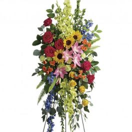 Tall standing floral spray with roses, lilies, sunflowers, and blue accents