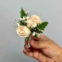 Small cream rose boutonniere with white filler flowers and greenery