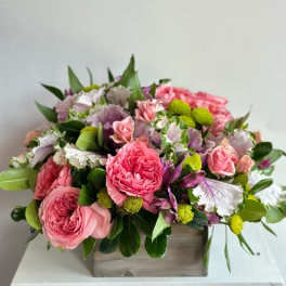 Pink roses and mixed blooms arranged in a wooden box