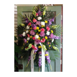 Tall standing spray of mixed pink, purple, white, and yellow flowers