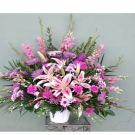 Pink lilies and mixed purple flowers in a white vase