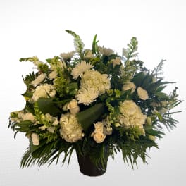 White floral arrangement in a black vase with mixed blooms and greenery