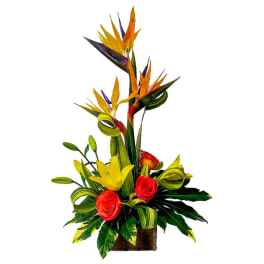 Tropical flower arrangement with bird of paradise and roses in a wooden container