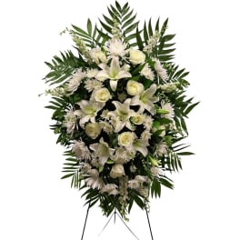 White floral standing spray with lilies, roses, and daisies on a stand