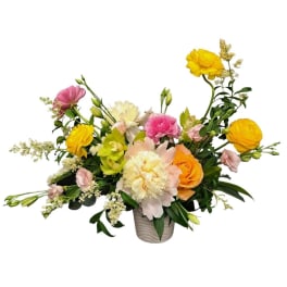 Mixed bouquet of yellow, pink, and peach flowers in a ceramic vase