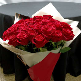 Bouquet of red roses wrapped in red and white paper with a ribbon