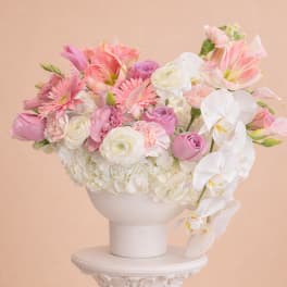 Pink and white floral arrangement in a white pedestal vase