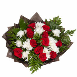 Bouquet of red roses and white chrysanthemums wrapped in dark paper