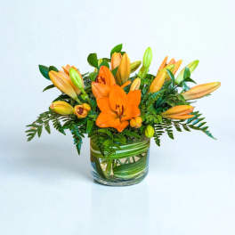 Orange lilies arranged in a clear glass vase