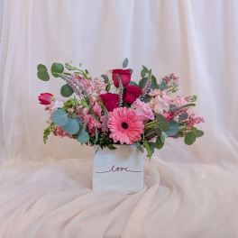 Pink and red mixed flower arrangement in a white box