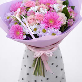 Pink and lavender bouquet with gerbera daisies, roses, and daisies wrapped in purple paper
