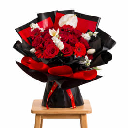 Bouquet of red roses with white flowers wrapped in black and red paper
