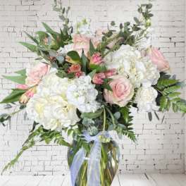 Large bouquet of pink and white flowers in a glass vase with a ribbon