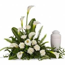 White calla lilies and roses arranged beside a white urn
