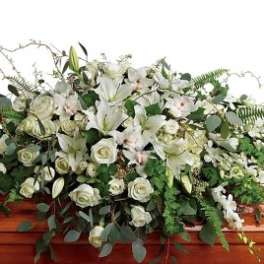 Large white rose and lily casket spray on a polished wood casket