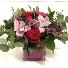 Pink and red floral arrangement in a square glass vase