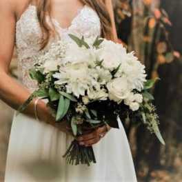 Bride holding a white bouquet with roses and daisies
