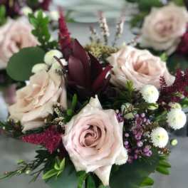 Bouquet of pale pink roses with burgundy accents and mixed greenery