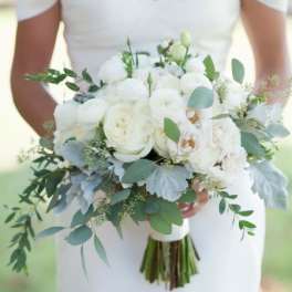 Bride holding a white bouquet with greenery