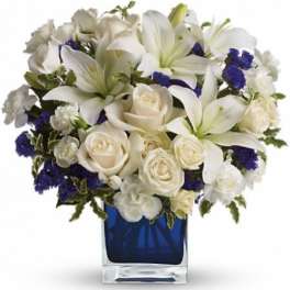 White lilies and roses arranged in a blue glass vase
