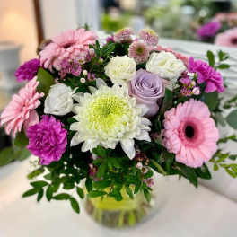 Mixed bouquet of pink gerbera daisies, roses, and a large white mum in a clear glass vase